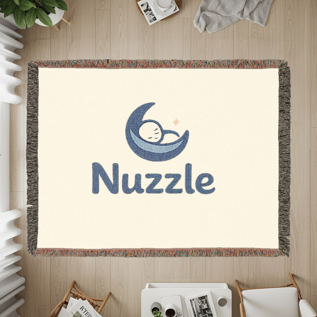 Cream tapestry with blue "Nuzzle" text and a sleeping baby in a moon graphic.