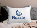 White pillow with Nuzzle logo featuring sleeping baby on moon.